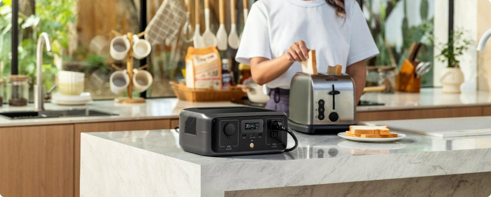 Person using a portable power station in a kitchen with a toaster on top