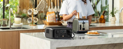 Person using a portable power station in a kitchen with a toaster on top