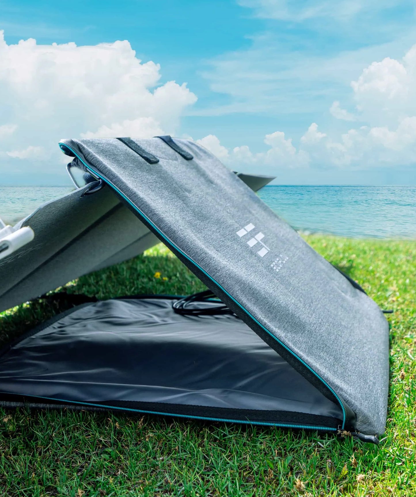 Portable solar panel on grass with ocean and sky in the background